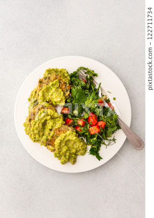 Enjoy a healthy breakfast with zucchini pancakes topped with green pea pesto, served with a mixed salad of fresh seasonal vegetables and herbs for a nutritious start Enjoy a healthy breakfast with zucchini pancakes topped with green pea pesto, served with a mixed salad of fresh seasonal vegetables and herbs for a nutritious start 122711734