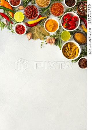 Colorful herbs and spices scattered across a gray surface, ideal for creating authentic and flavorful dishes, top view and copy space 122711759