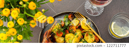 Baked rabbit with potatoes and carrots, a set table with food, a glass of wine and a vase of flowers Baked rabbit with potatoes and carrots, a set table with food, a glass of wine and a vase of flowers 122711777