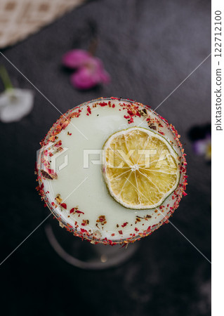 Elegant citrus cocktail in tall glass with floral garnish and dried lime slice, perfect for summer 122712100
