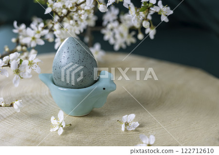 Easter chicken stand with an egg on a wooden background and blossoming plum branches. 122712610