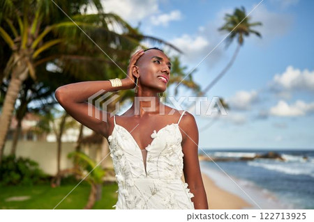 Gender fluid person in elegant wedding dress, serene tropical beach. Ocean waves, palm trees swaying. LGBTQ-friendly bridal moment. Inclusive destination ceremony. Unique non-binary bridal fashion. Gender fluid person in elegant wedding dress, serene tropical beach. Ocean waves, palm trees swaying. LGBTQ-friendly bridal moment. Inclusive destination ceremony. Unique non-binary bridal fashion. 122713925