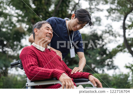 Healthcare professional providing joyful care to senior man in wheelchair, highlighting trust and comfort 122716704