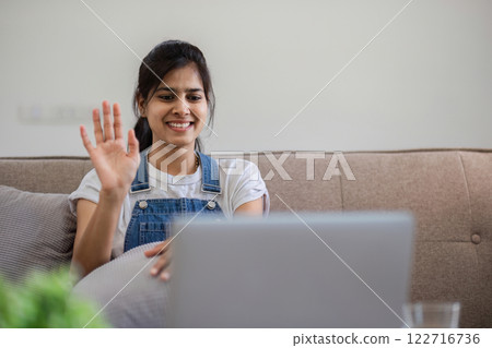 Woman Engaged in Video Call from Cozy Living Room Setting with Modern Decor and Comfortable Ambiance Woman Engaged in Video Call from Cozy Living Room Setting with Modern Decor and Comfortable Ambiance 122716736