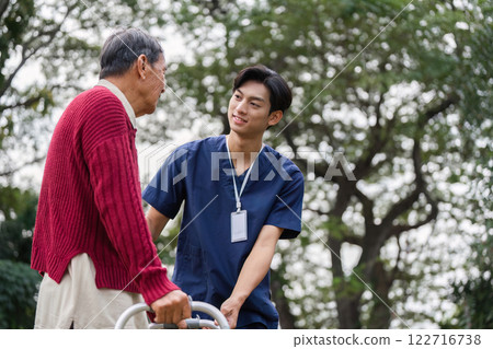 Elderly man and healthcare worker sharing an encouraging moment outdoors while using a walker 122716738