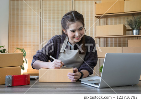 SME business entrepreneurs small in Asia Write shipping information on a cardboard box in home office. Small business operators preparing to ship to customer SME business entrepreneurs small in Asia Write shipping information on a cardboard box in home office. Small business operators preparing to ship to customer 122716782