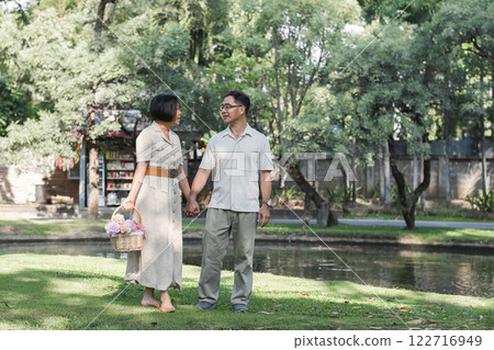 A retired couple walks outside together in the park on a relaxing vacation. A retired couple walks outside together in the park on a relaxing vacation. 122716949