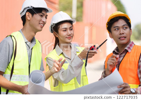 Construction professionals discussing project plans with blueprints at a bustling construction site 122717035