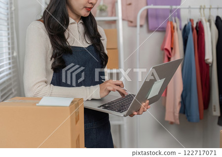 Young woman online seller managing e-commerce business with laptop in modern boutique setup Young woman online seller managing e-commerce business with laptop in modern boutique setup 122717071