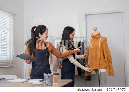 Fashion designers discussing design details while presenting a cozy sweater on a mannequin 122717072
