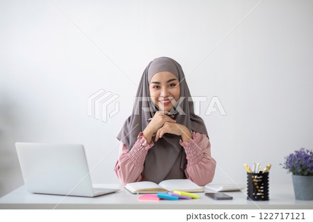 Smiling Muslim business woman Wearing a hijab while chatting online on a work desk in the office. 122717121