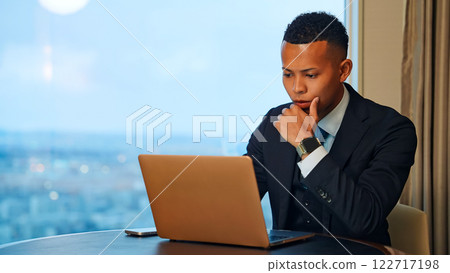 Businessman working on a laptop in a high-rise office 122717198