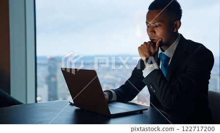 Businessman working on a laptop in a high-rise office 122717200