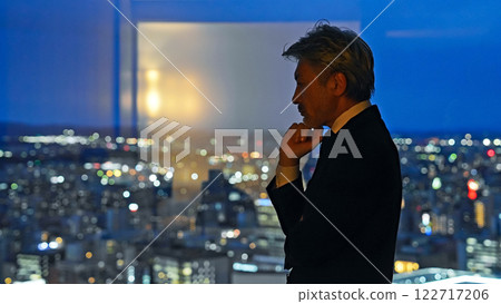 A business person thinking with a city night view in the background A business person thinking with a city night view in the background 122717206