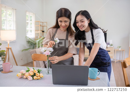 Middle-aged daughter happily arranges flowers with her mother at home Free time activities that are done together as a family Middle-aged daughter happily arranges flowers with her mother at home Free time activities that are done together as a family 122717250