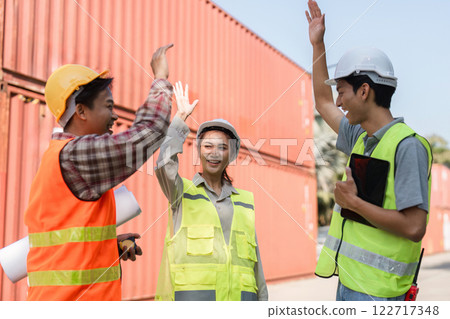 Construction team celebrating success with high-fives near shipping containers at a worksite Construction team celebrating success with high-fives near shipping containers at a worksite 122717348