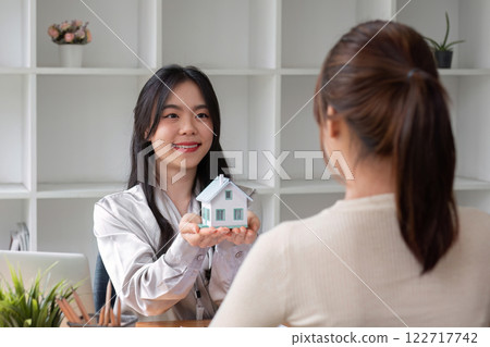 Home sales and real estate agent provide home models to clients to complete sale contract with. Home sales and real estate agent provide home models to clients to complete sale contract with. 122717742