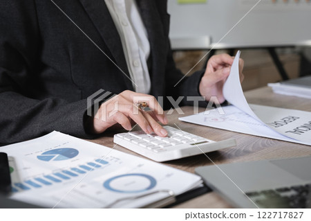 Asian female accountant working on calculations on table in office Asian female accountant working on calculations on table in office 122717827