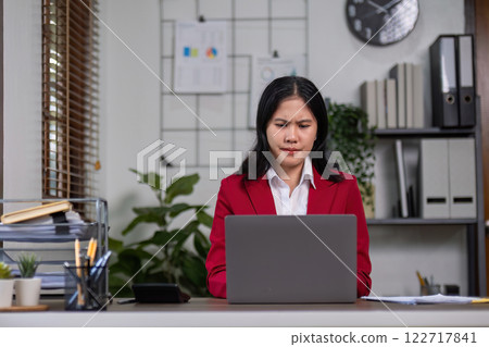A determined businesswoman is sitting with stress in her home office. 122717841