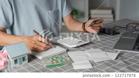 Elderly man planning savings with a calculator and credit card at home office Elderly man planning savings with a calculator and credit card at home office 122717878