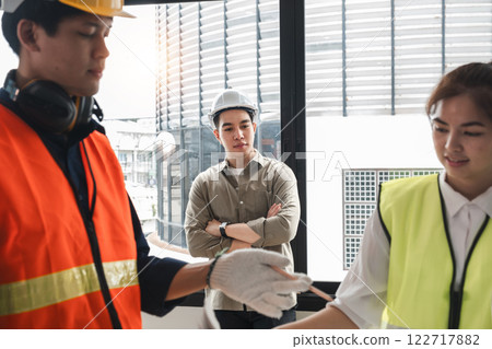 Handsome young chief engineer standing during engineer team discussion at construction site 122717882