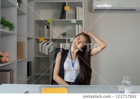Relaxed businesswoman stretching in a modern office after managing work-related stress 122717892