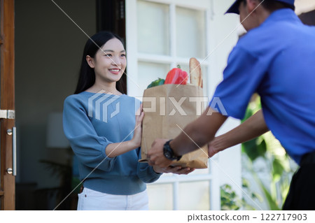 delivery man Deliver a paper bag package to the beautiful woman at the front of the house according to the order. delivery man Deliver a paper bag package to the beautiful woman at the front of the house according to the order. 122717903