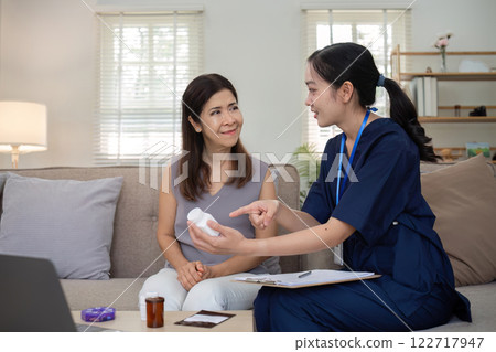 A caregiver is giving advice on health care and medication to an elderly woman at home. A caregiver is giving advice on health care and medication to an elderly woman at home. 122717947