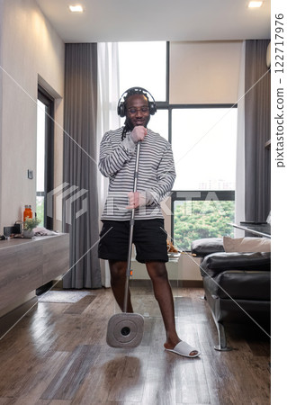 Playful African man in casual clothes Clean the dust or dirtiness of the room happily and have fun cleaning. Playful African man in casual clothes Clean the dust or dirtiness of the room happily and have fun cleaning. 122717976