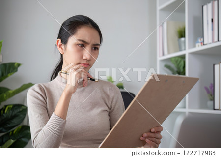 Asian businesswoman feeling tired and stressed over an unsuccessful business while working in a home office decorated with soothing green plants. Asian businesswoman feeling tired and stressed over an unsuccessful business while working in a home office decorated with soothing green plants. 122717983