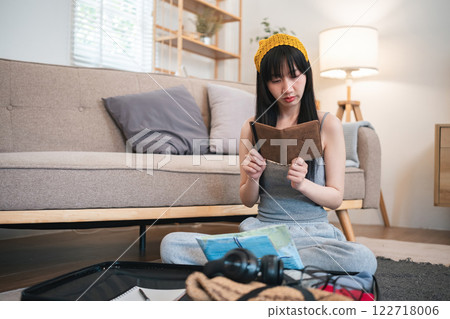 Beautiful young women checks list of items and clothes to pack in her suitcase for a holiday trip. Beautiful young women checks list of items and clothes to pack in her suitcase for a holiday trip. 122718006