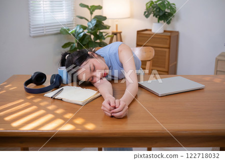 Asian college student who is bored Sitting in front of a laptop studying online through a video calling program on a laptop at home. 122718032