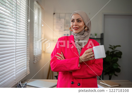 Confident Muslim businesswoman standing in front of desk in office 122718108