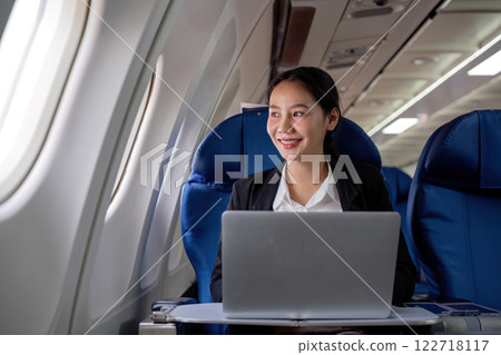 A young business woman travels to work outside the city by flying in business class. and work on airplanes with laptops A young business woman travels to work outside the city by flying in business class. and work on airplanes with laptops 122718117