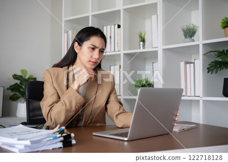 Unhappy Asian business woman shows stress over unsuccessful business while working in home office decorated with soothing green plants. 122718128