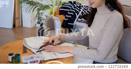 beautiful young woman sewing Repair damaged clothes so that it can be reused. In order to reduce the creation of waste and reduce environmental pollution. 122718169