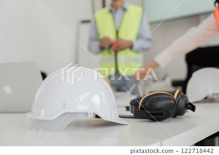 Construction team preparing safety equipment for site meeting with helmets and ear protection 122718442
