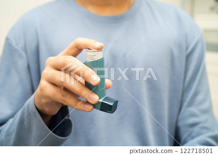 Asthma and chronic obstructive pulmonary disease COPD, Asian young man using metered dose inhaler MDI. 122718501
