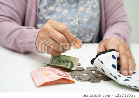 Asian senior or elderly old lady woman holding counting coin money in bag. Poverty, saving problem in retirement. 122718552