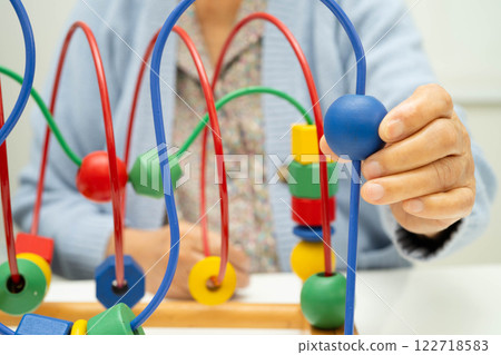 Asian elderly woman playing enhancing skill board game. 122718583