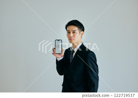 A young man in his twenties holding a smartphone 122719537