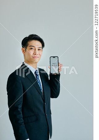 A young man in his twenties holding a smartphone 122719539