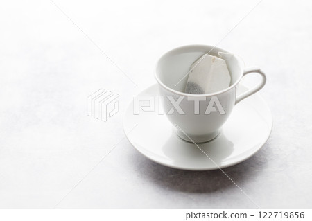 Cup of hot tea with tea bag on white table background. Cup of hot tea with tea bag on white table background. 122719856