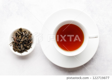 Cup of hot tea with tea leaf on white table background. 122719877