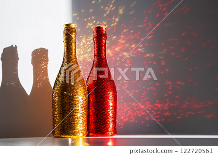 Glittering champagne bottles casting colorful sparkling on the wall. Glittering champagne bottles casting colorful sparkling on the wall. 122720561