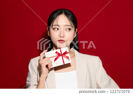 Fashionable young woman holding gift box 122721078