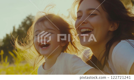 Happy mother and daughter laughing together in a field at sunset 122721241