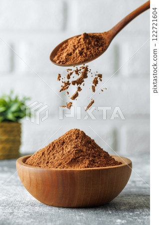 cocoa powder falling from spoon in bowl on table 122721604
