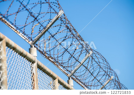 Barbed wire fence symbolizing border control, geopolitical tensions, and restricted freedoms in modern society. Barbed wire border security fence. Barrier border. Boundary security wall. Private area. 122721833