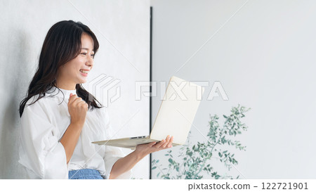 A woman doing a fist pump using a laptop in a room 122721901